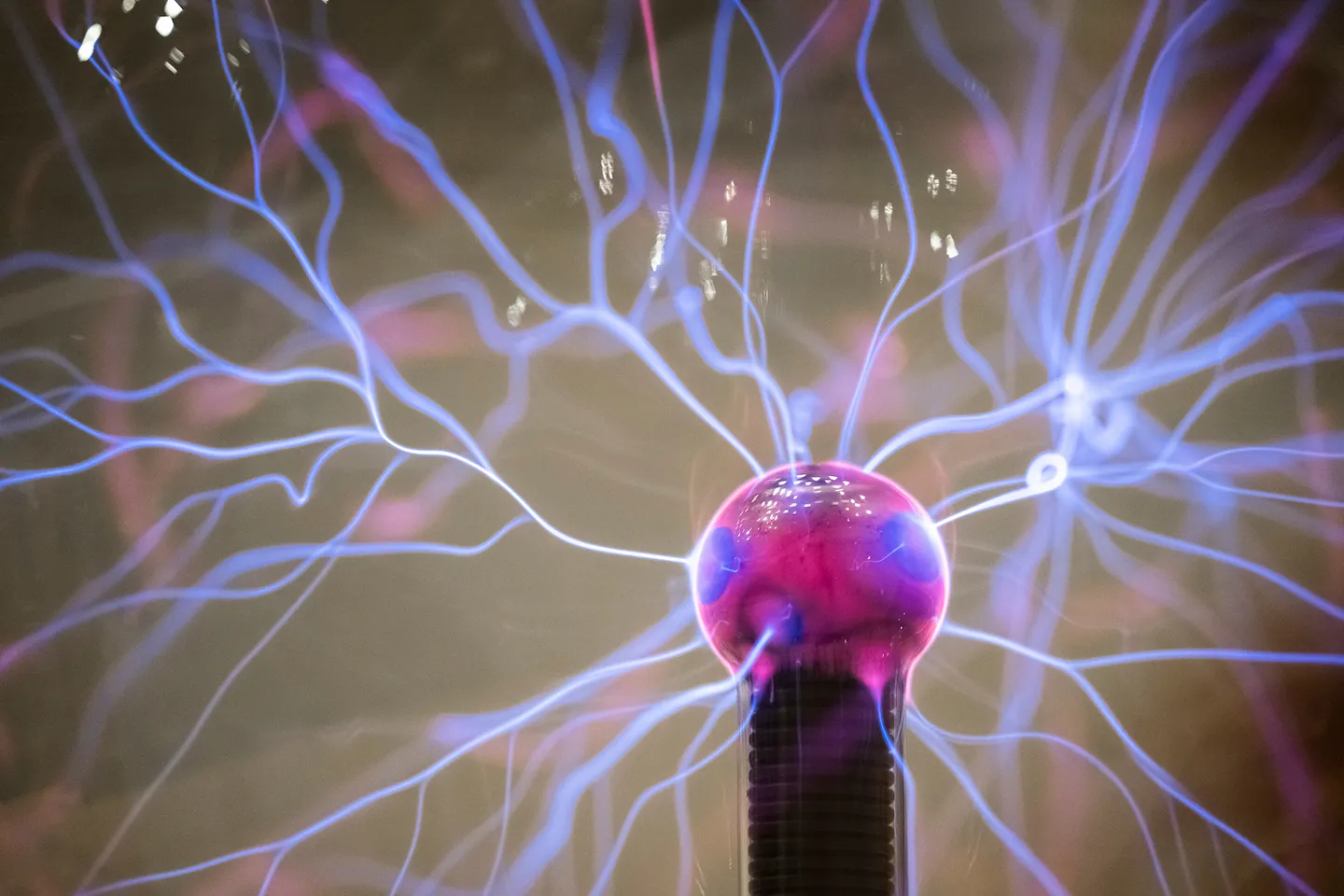 Threads of blue electricity spiderweb out from glowing purple plasma ball